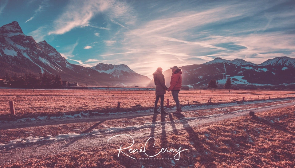 Fotograf René Cerny – Reisefotografie. René und Eugenia halten Händchen in den verschneiten Alpen bei Sonnenuntergang.