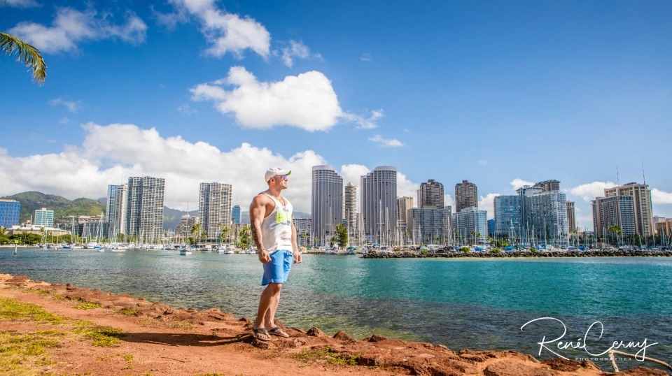 Fotograf René Cerny – Reisefotografie. René sitzt auf Felsen mit Blick auf die Skyline von Honolulu, Hawaii.