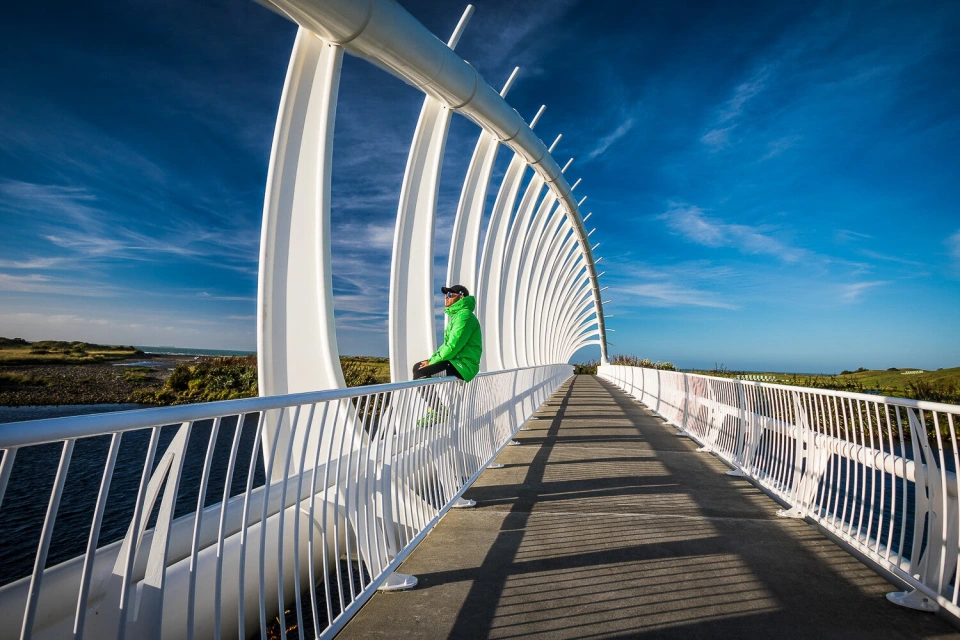 Fotograf René Cerny – Reisefotografie. René sitzt auf dem Geländer der Te Rewa Rewa Bridge, Neuseeland.