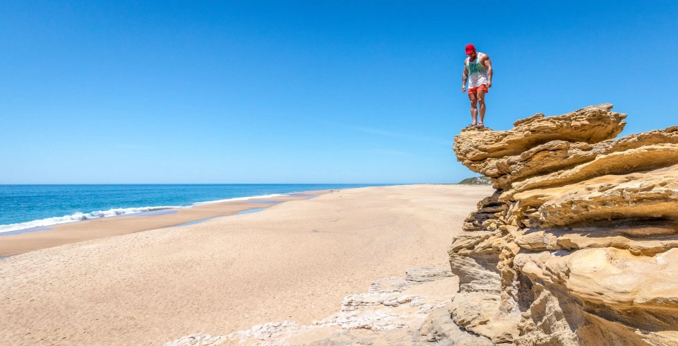 Fotograf René Cerny – Reisefotografie. René steht auf einer Felsklippe über dem Meer, Algarve, Portugal.