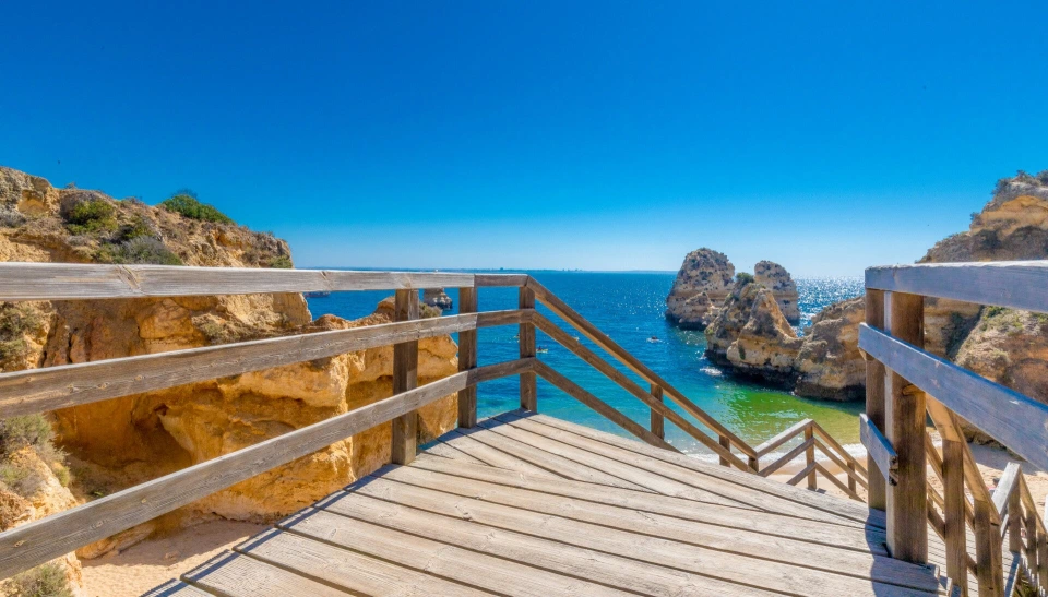 Fotograf René Cerny – Landschaftsfotografie. Holzsteg zum Strand mit Felsformationen, Algarve, Portugal.
