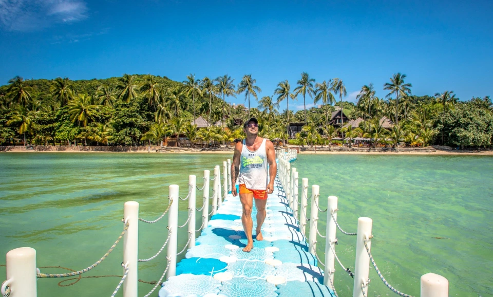 Fotograf René Cerny – Reisefotografie. René geht über einen Holzsteg durch eine türkisfarbene Lagune, Thailand.