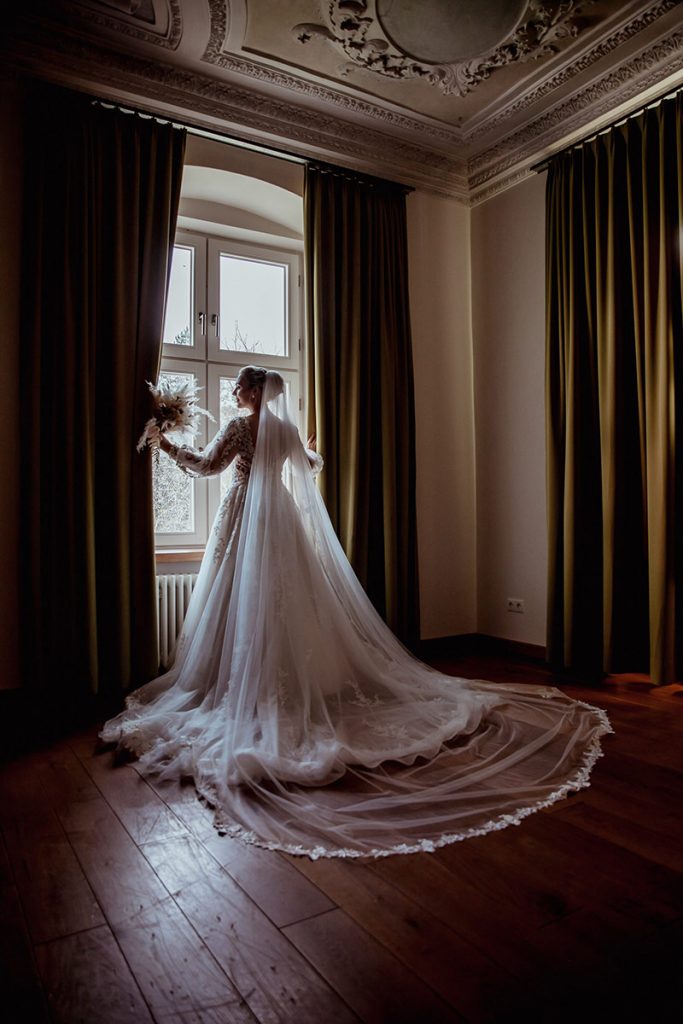 Braut auf dem Hotelzimmer Wunderschöne Winterhochzeit. Braut steht vor dem Fenster