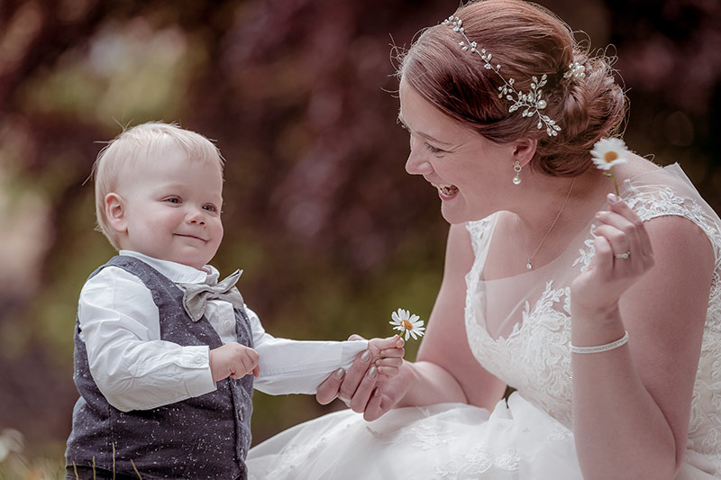 Braut mit Kind in eine Blumenwiese.